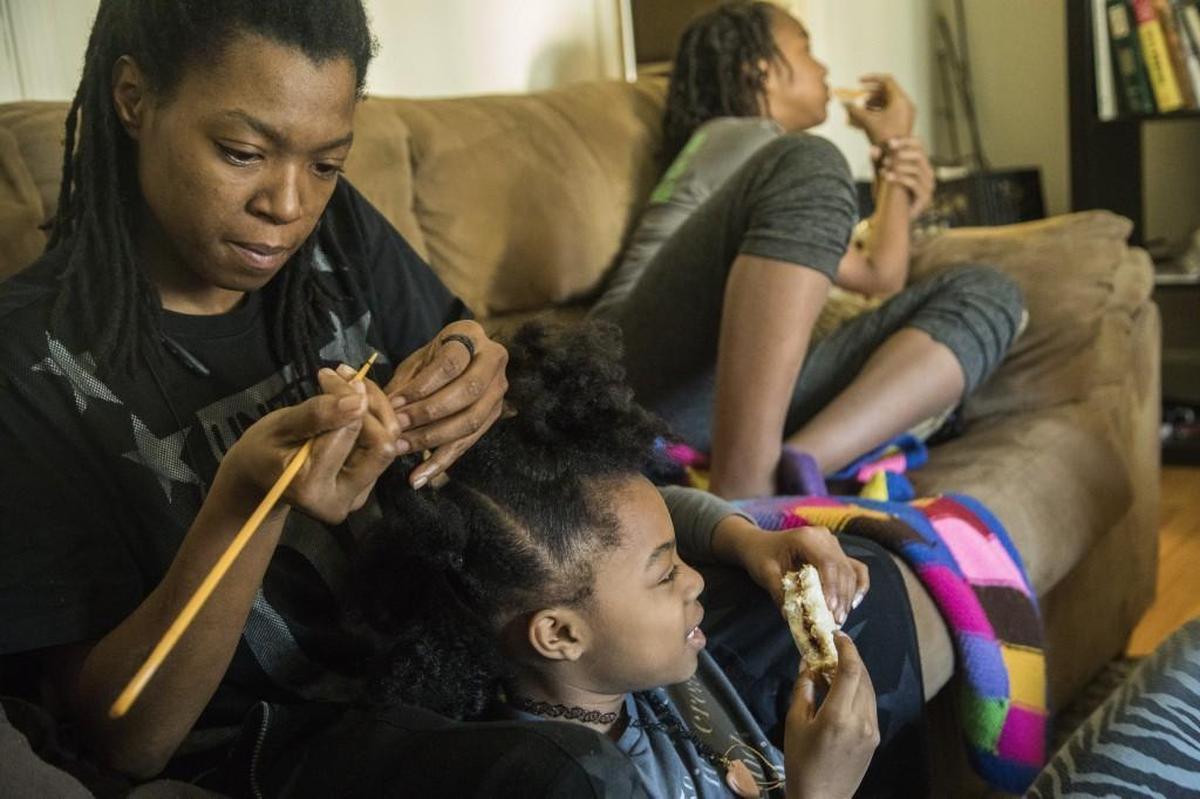 Vanessa Bates grooms her 8-year-old daughter Audrey Hatcher’s hair at Bates's mother's home in Durham. Homeless and without a car, Bates has struggled to find steady employment and sleeps on the couches and floors of family and friends.
