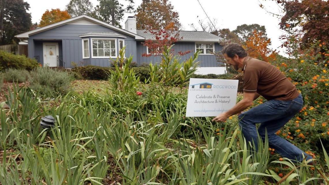 While walking down Bradley Place near his home, Ridgewood neighborhood resident Greg Kelly straightens up a neighbor's fallen sign Thursday. Kelly is helping to promote a feeling of community in the Ridgewood neighborhood, a 1950s era community of ranch style one story homes that are hoping to combat a trend to tear down the older homes there and build much larger new homes that are not characteristic of the small family neighborhood.