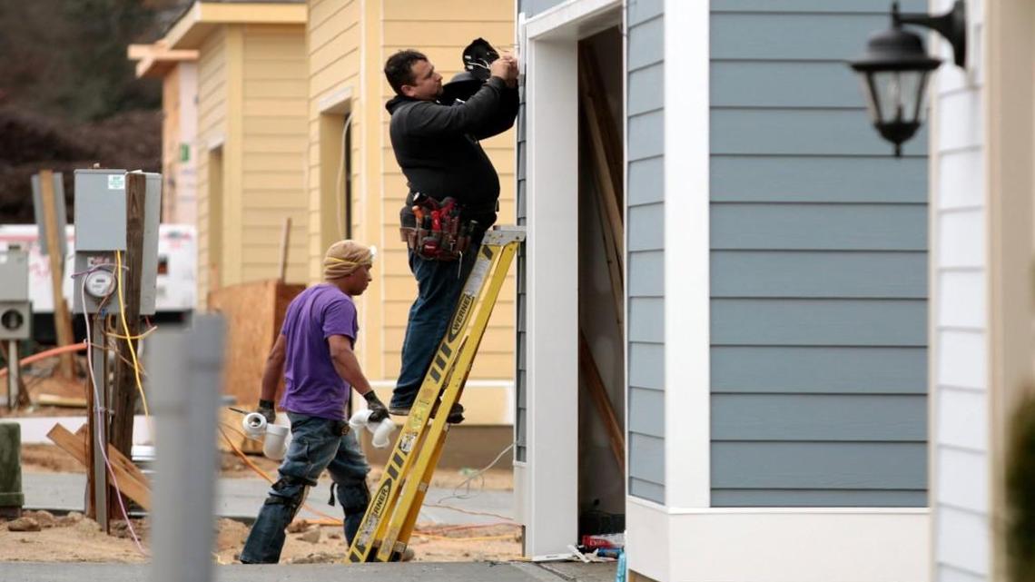An electrician installs a rear exterior garage entry light on new homes on Beardall Street near Interstate 540 in December 2015. Growth, development and traffic have been big issues in northeast Raleigh.