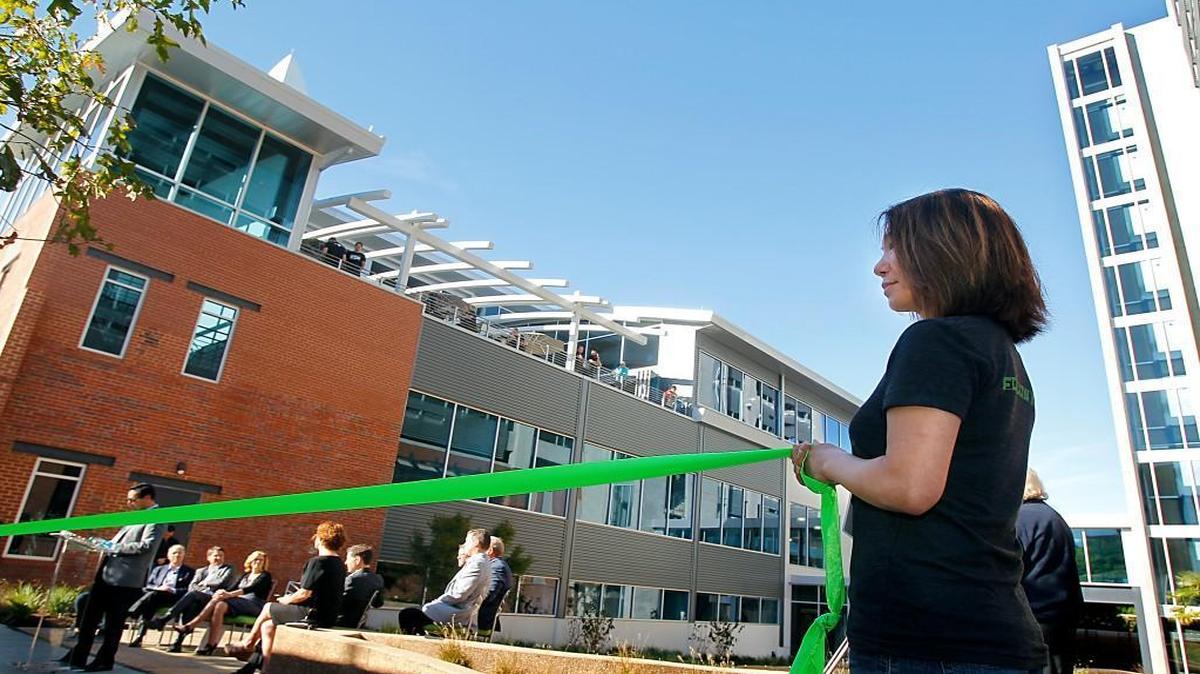 Muxia Eichelsdorfer, right, an engineer at Citrix, helps to hold the official the ribbon before a cutting ceremony to celebrate the public opening of the new office building in downtown Raleigh, N.C. in 2014. The city is re-evaluating the responsibilities of its economic development manager position.
