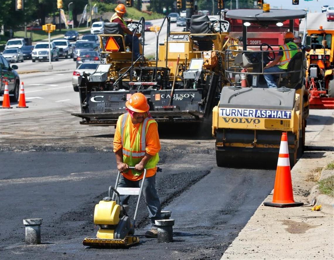 Heavy paving equipment in the background waits Thursday morning, July 14, 2016 for a paving crew member for Turner Asphalt of Raleigh, NC to use a small asphalt compactor to smooth over hot 200-300 degree asphalt between water valve access pipes on Capital Boulevard. Turner Asphalt crews have been working on a water pipe break in the 2900 block of southbound Capital Boulevard near the Brentwood Road intersection since Wednesday night to pave over three lanes wide several hundred foot long section of Capital Boulevard that was torn up for the water pipe break Wednesday afternoon. The repairs and paving are set to be completed by 9am on Friday due to the heat and paving requirements.