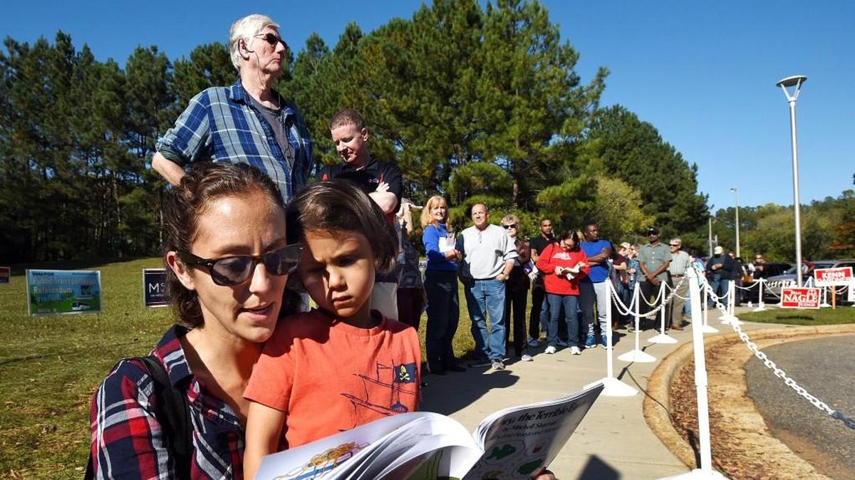 Jill Grifenhagen reads a book to her son, Linus, as they wait in line for early voting at the Lake Lynn Community Center in Raleigh, N.C. Wednesday, October 26, 2016.