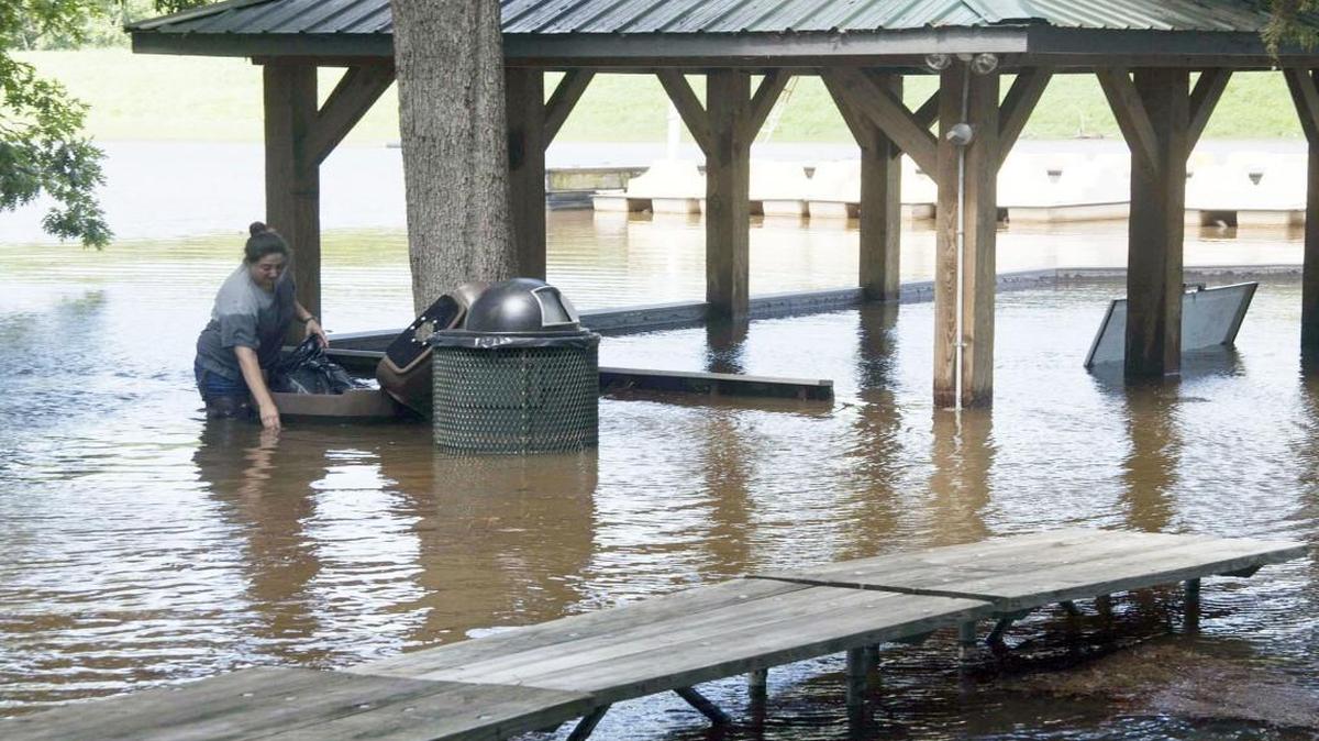 Tracy Filonena cleans up the flooded Bond Lake waterfront at Bond Park in Cary on Wednesday Aug. 13, 2014. Heavy rains raised the water level in the lake by several feet, flooding some of the low-lying waterfront buildings and picnic benches.