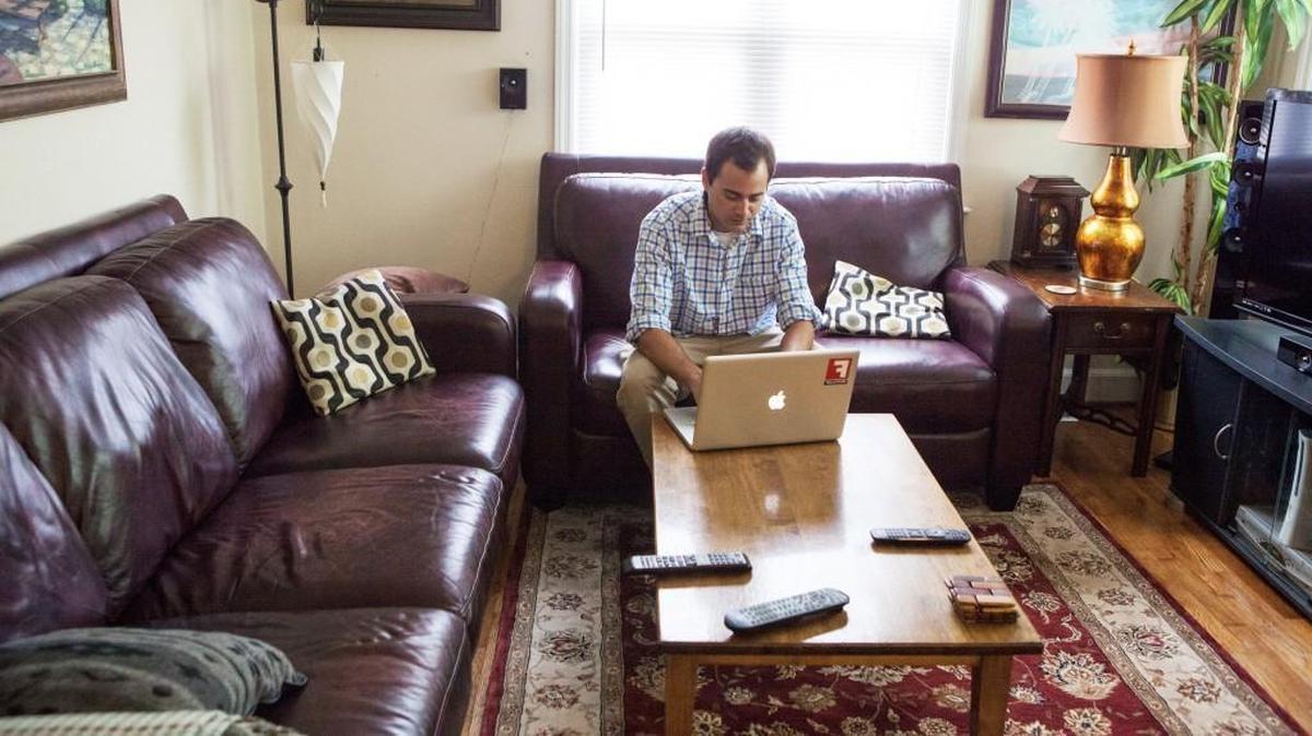 Dennis Gugger uses his computer after work on Aug. 11, 2014, in Raleigh. Gugger and his roommate used the app Airbnb to rent their house to travelers.