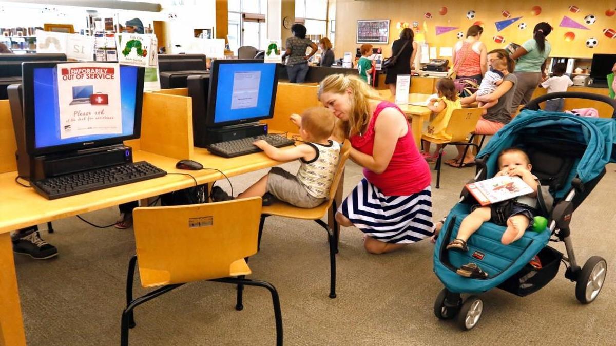 From left, 2 year old Samuel Price gets guidance in how to use the kids computer terminal from his mom Malisa Price of Raleigh, as her younger son, Gideon Price, 1, is content to chew on a children's book in the Children's area of the Cameron Village Regional Library Wednesday, July 13, 2016. The popular inside the beltline public library will close July 31, 2016 for a several month renovation effort and will reopen by mid-October 2016 said library manager Robert Lambert. The two story, 30,000 square foot library will get new carpeting, a new color scheme and paint, new furniture, a reconfiguring of the open spaces for more tables along with an improved children's room.