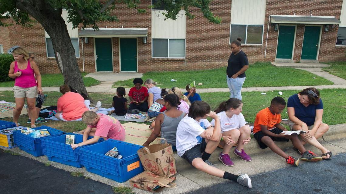
Faculty and families from Lacy Elementary School spread out blankets and books from their Bookmobile during a weekly visit with children on Raleigh Boulevard on Tuesday, July 14, 2015 in Raleigh, N.C.
