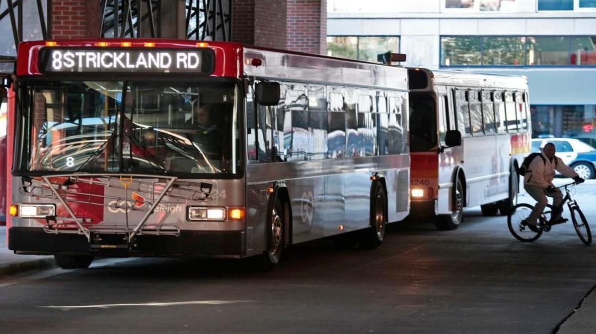 A bicyclist takes off from between two GoRaleigh city buses at the Moore Square station hub downtown Raleigh on Feb. 19, 2016.