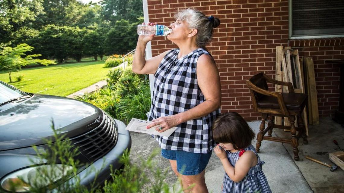 Lynda Martin drinks bottled water with her granddaughter Izabelle Hinrichs, 3, Wednesday, June 29, 2016 at their Bond Street home in Raleigh. "I won't make coffee with it. It tastes bad and smells like sewer," said Martin of her well water. The Trawick Dale neighborhood, near the intersection of Bond Street and Trawick Road, is surrounded by the City of Raleigh but fought annexation and remains in the county. Pesticide contamination was discovered in some of the resident's wells in 2012, and now some are working to try and get the commissioners to fund city water lines so residents can get clean drinking water.