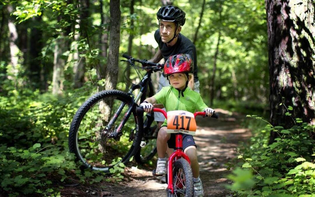 
Mitchell Quinn helps his daughter, 4-year-old Bridget, along the trail during an annual festival hosted by Triangle Off-Road Cyclists at Lake Crabtree Park on in Raleigh on June 21. The city is updating its bicycle plan, which could lead to more bike lanes and other features. 
