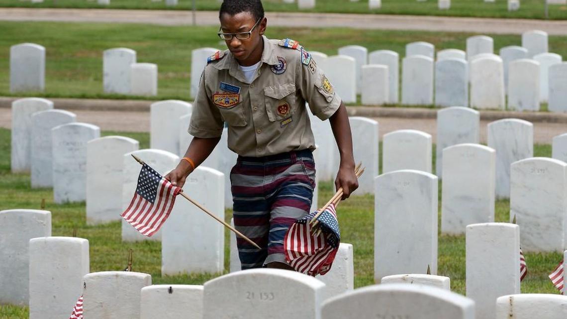 Patrick Mahon, 15, of Boy Scout Troop 515 in Wendell places American flags on the graves of fallen soldiers at the Raleigh National Cemetery Friday, May 27, 2016 in Raleigh, N.C. Boy and Girl Scout Troops from Wake County converged on the grounds of the cemetery to place over 1500 flags on the graves to honor their sacrifice during the Memorial Day celebration.