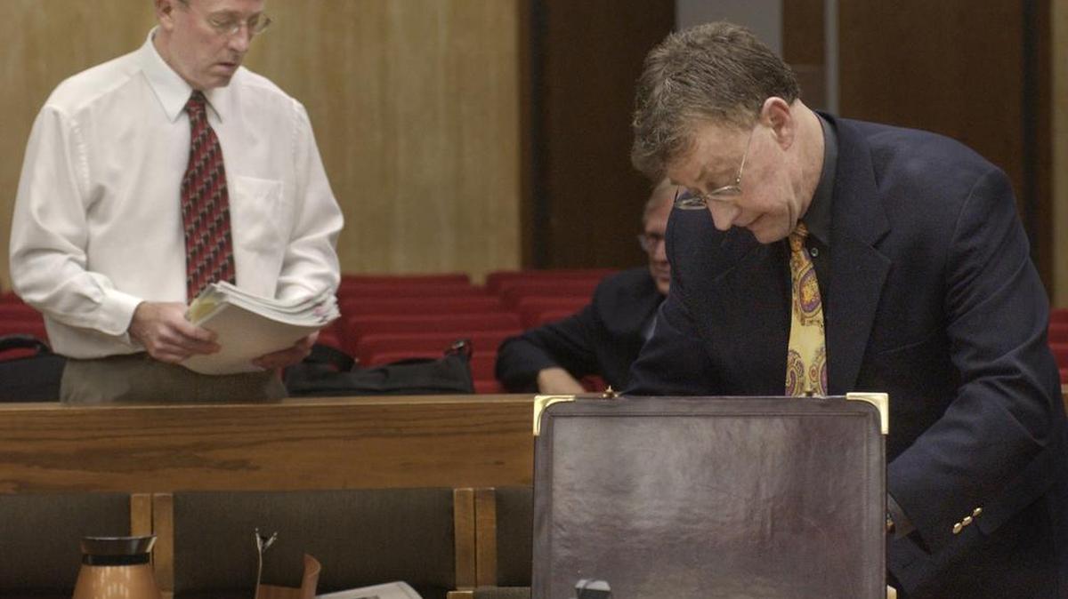 Michael Peterson (at right) unpacks his briefcase as his brother Bill Peterson (at left) carries a stack of documents June 10, 2003 in the Durham County Courthouse.