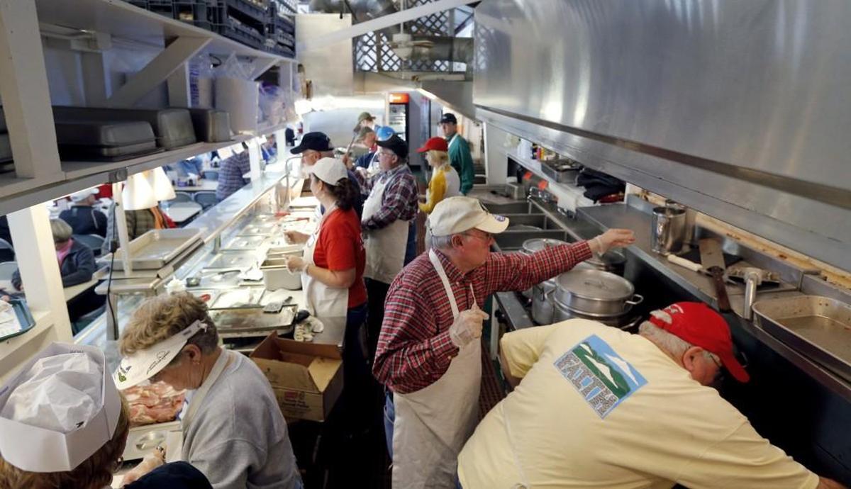A kitchen crew of at least a dozen people scurry to fill orders at the NC State Fair booth operated by The First United Methodist Church of Cary and White Plains United Methodist Church on Monday, Oct. 19, 2015.