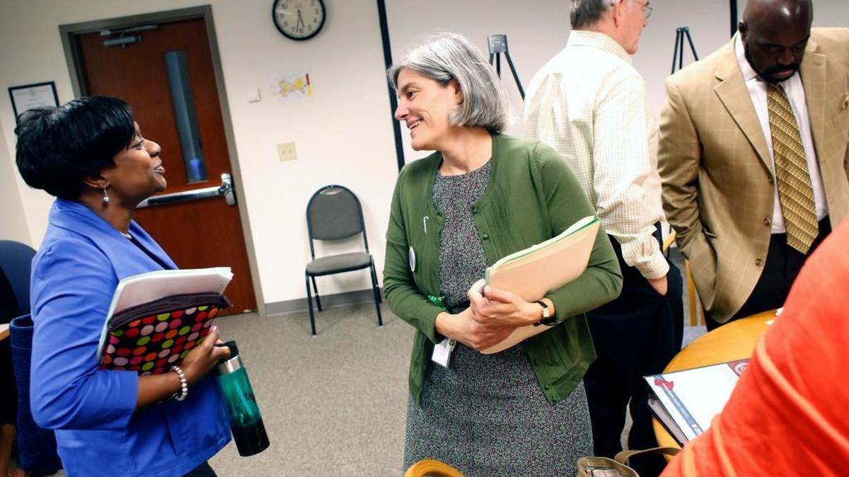 School board member Christine Kushner, center, congratulates Monika Johnson-Hostler, left, on her successful bid for school board member following a Wake County school board work session in 2013