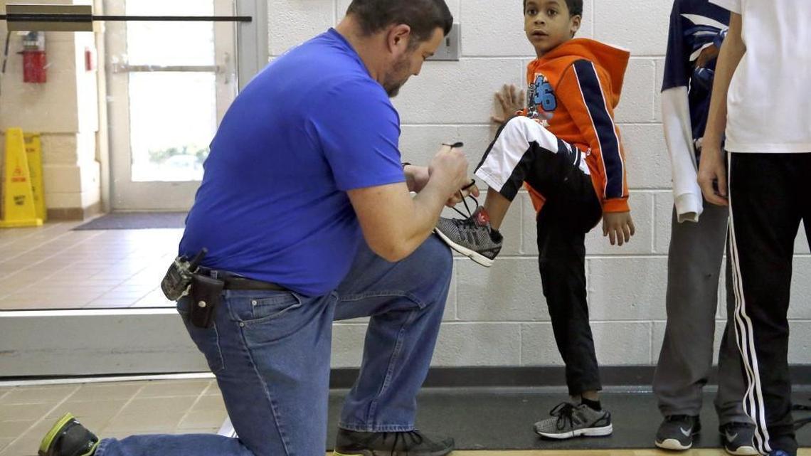 YMCA worker Joe Loftus, left, ties a shoe for Makhi Robinson as Wake County year-round students enjoy a game of kickball as they attend the Cary Family YMCA trackout program in this 2016 file photo. The YMCA is among the groups that will provide socially distanced learning centers for Wake County students during the COVID-19 pandemic.