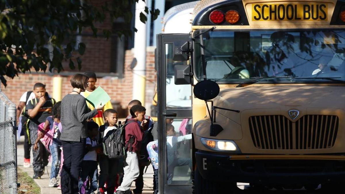 A Hunter Elementary School staffer sees her student charges safely to their school bus at Friday afternoon, October 30, 2015 at the end of the school day in east downtown Raleigh.