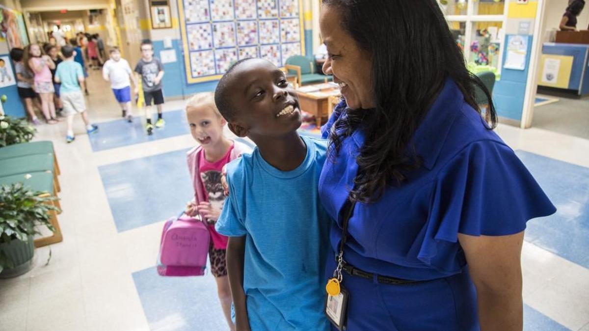 Principal Rhonda Jones gets a hug from second-grader Kaba Mbugua Thursday, June 23, 2016 at Rand Road Elementary School in Garner. Rand Road is among dozens of single-track year-round schools in the state that could be forced to switch to a traditional calendar later this summer if a Senate budget provision is approved that mandates that multi-track schools are the only ones allowed under state law.