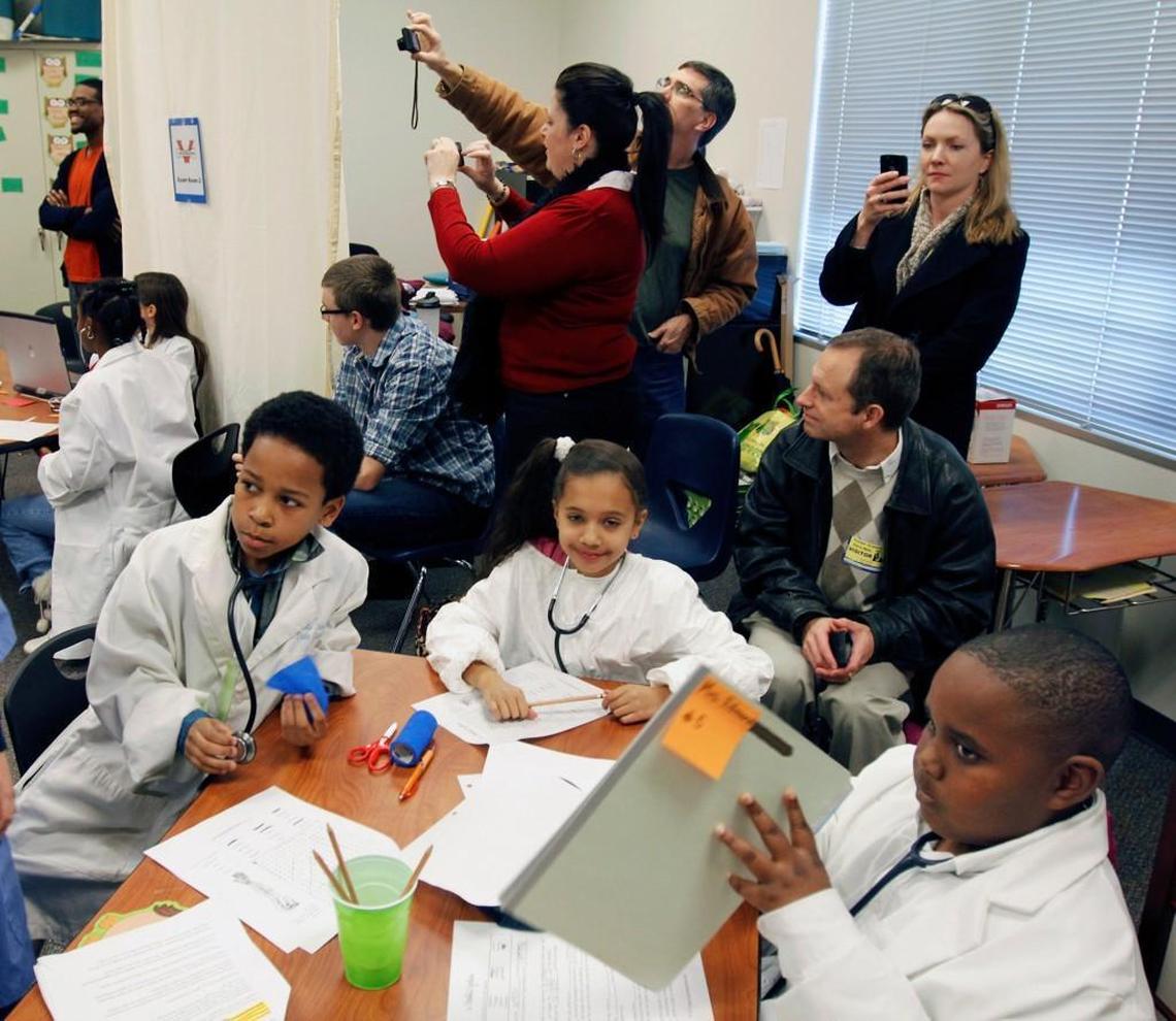 Parents watch and photograph Voyager Academy third graders participating in a learning project: how a doctor's office operates. Their classroom became a simulated exam room. Voyager is Durham's largest charter school.