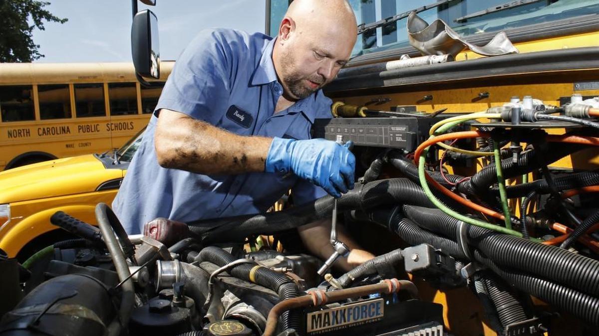 Mechanic Randy Jones replaces a turbo atop the engine of a Wake County school bus at the Wake County Public School System transportation garage in southeast Raleigh Thursday, August 25, 2016.