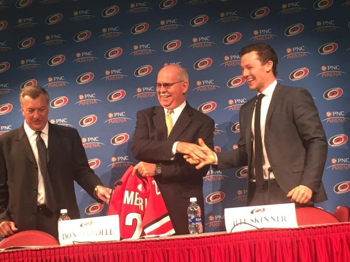 Wake County Superintendent Jim Merrill, center, shakes hands with Carolina Hurricanes player Jeff Skinner after getting a jersey to mark a new program to encourage students to read more. On the other side of Merrill is Don Waddell, president of the Hurricanes.
