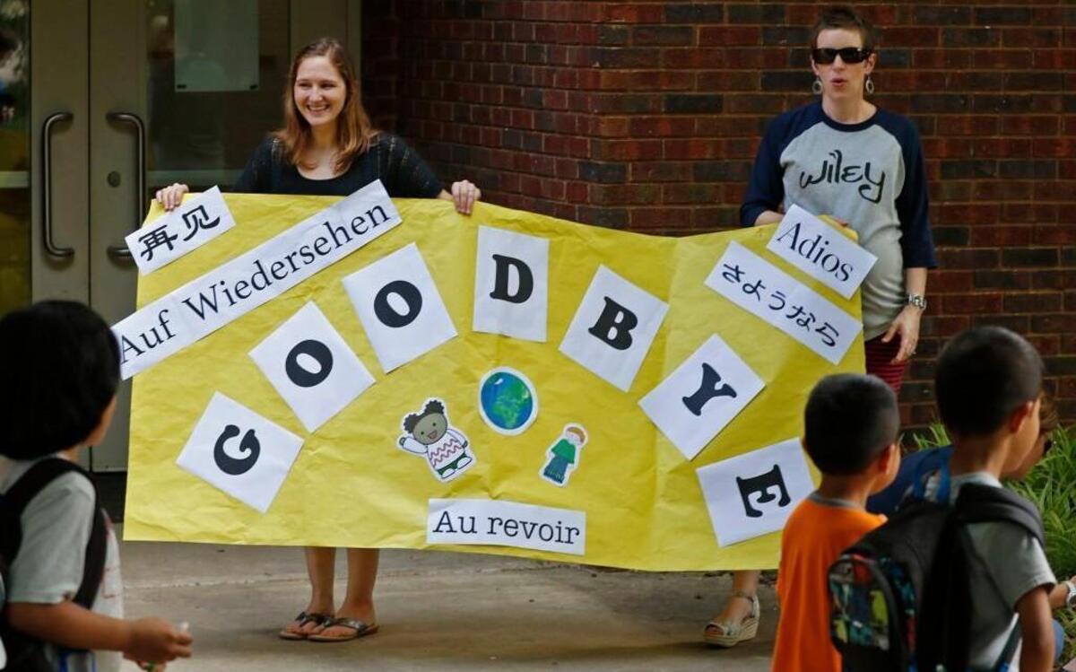 
Wiley Magnet Elementary School teachers Sadie Hoover and Chris Gower-Hahner hold a multi-lingual banner for students departing on the last day of class on June 8, 2015. Wiley is one of five WCPSS magnets that will be asked to diversify their enrollments by accepting more lower-performing and lower-income students.
