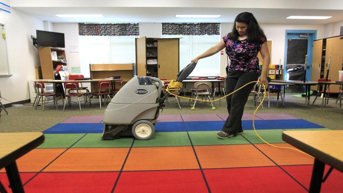Delmi Umana, head custodian at Hodge Road Elementary School in Knightdale, N.C., cleans the rug in a classroom at the school Tuesday, July 26, 2016.