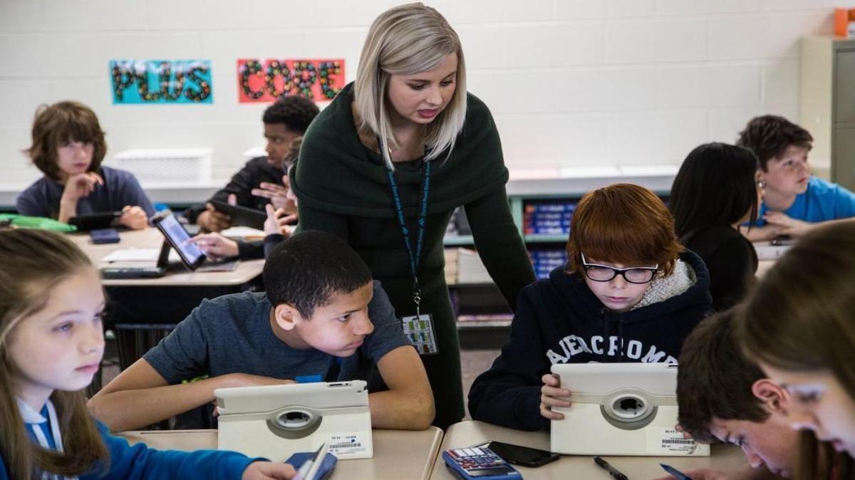 Durant Road Middle School teacher Alyssa Jackson helps seventh-graders Jayon Whitley, left, and Joe Abi-Najm during a lesson on statistics analyzing NCAA mens basketball seeds at the Raleigh school on March 16, 2017. Gains in middle school performance helped increase passing rates statewide.