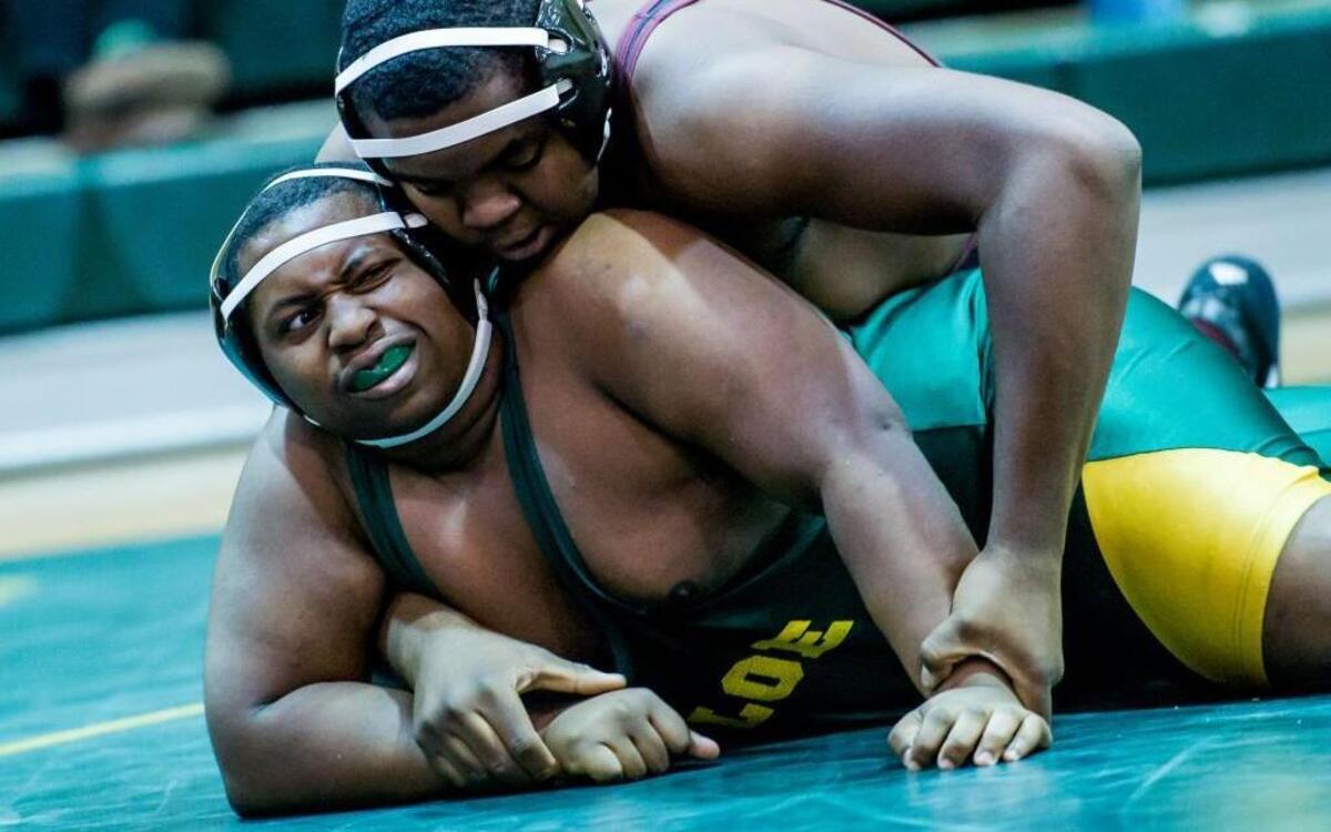 Wakefield High School’s Daniel Oloyede (top) and Enloe High School’s Adam Clark wrestle in the heavyweight class during the match in Raleigh on Dec. 10, 2014. Clark is a student at Wake Early College of Health and Sciences who plays sports at Enloe.