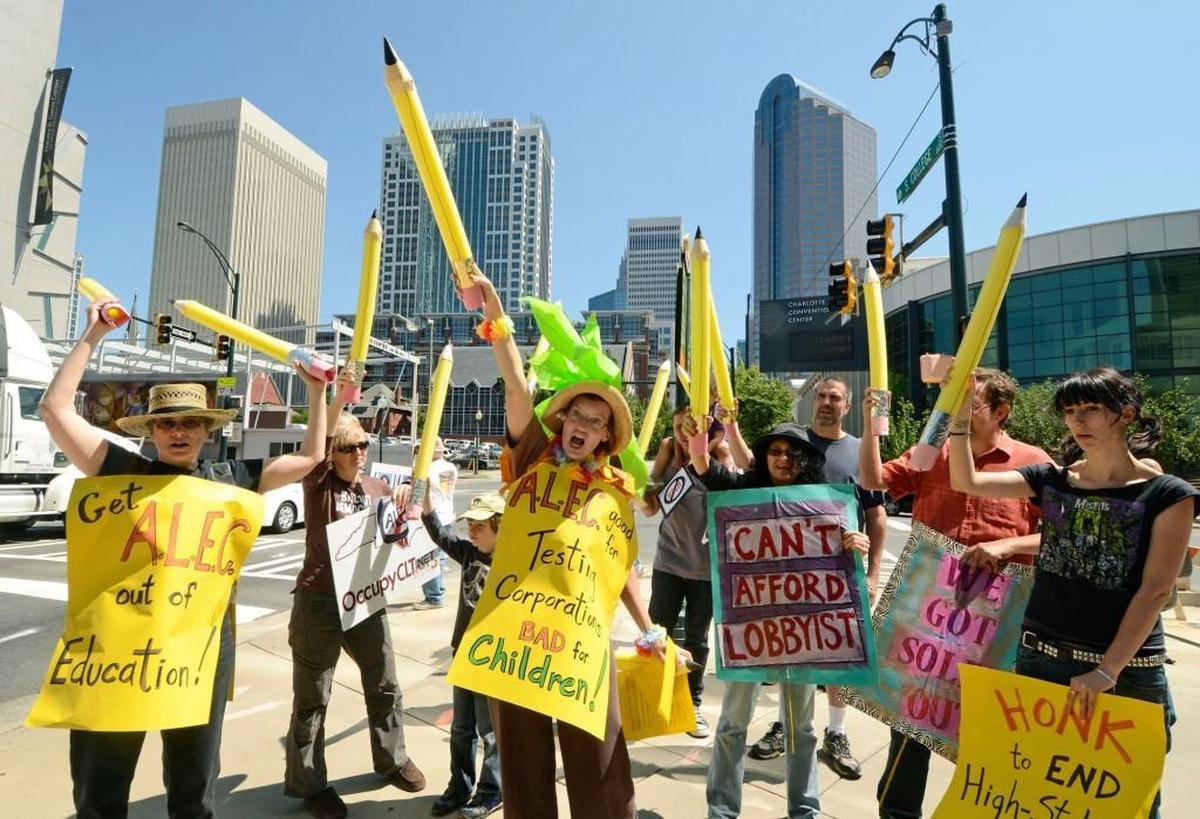 Mecklenburg ACTS, a local group opposed to high-stakes testing, demonstrates using a routine with oversized pencils led by Pamela Grundy (center with yellow sign holding up pencil) )outside the Westin on May 11, 2012, where a conference that involved test-makers was taking place.