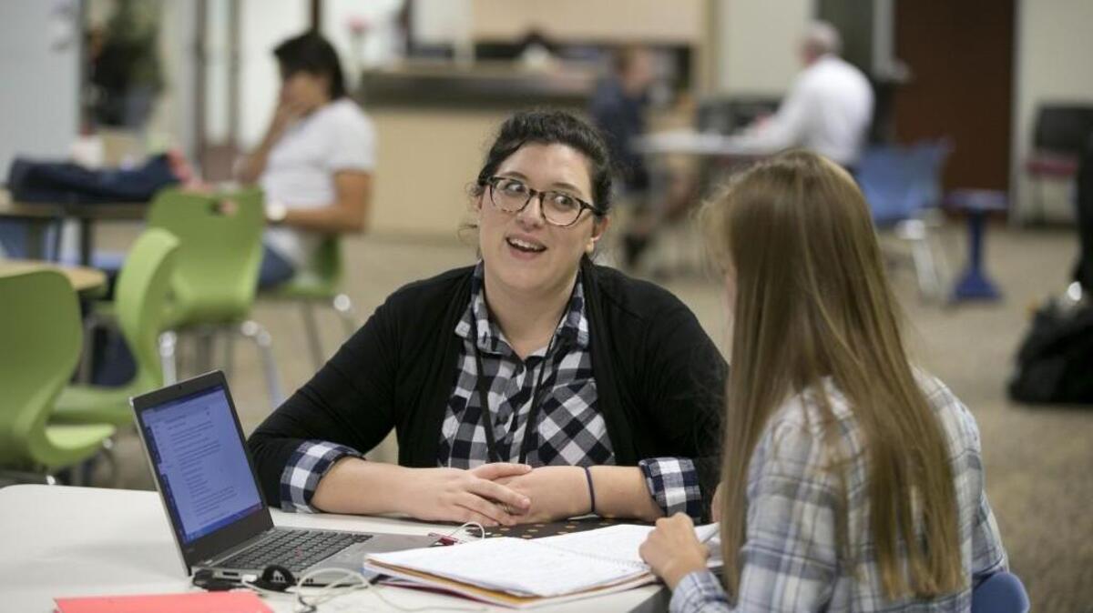 Crossroads Flex High School social studies teacher Kasey Turcol, left, works with student Alina Efimova  in this 2016 file photo. Crossroads FLEX has temporarily switched to only online courses but will resume in-person instruction later this school year by offering some classes at Cary High.