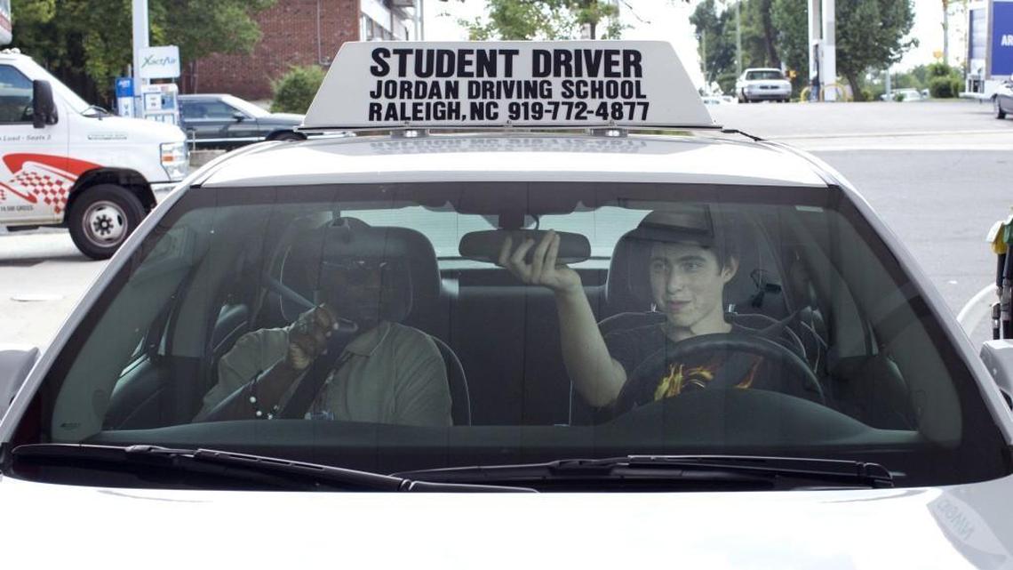 In this file photo, a 15-year-old student driver adjusts his mirror at the direction of instructor Curtis Wilson during the behind-the-wheel portion of his driver’s education program in Zebulon, N.C.