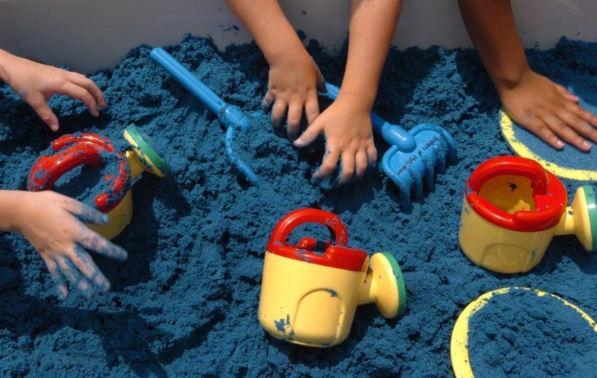 Holly Grove Elementary School kindergarteners play in tubs of blue sand on the first day of school in this 2007 file photo. It’s among eight multi-track year-round schools that will change calendars over the next two years.