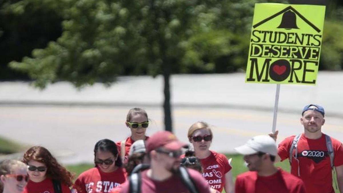 Justin Smith, a Students Deserve More protest marcher (with sign), is a High Point Central High School teacher who began his two-day, multi-mile march to the NC Legislature with about 15 other teachers, students and parents from across North Carolina at Wakefield High School in North Raleigh Tuesday afternoon. The group is one of two. The other group started marching Tuesday afternoon from eastern Durham County. Both are bound for the the Legislature for a rally Wednesday afternoon and potential meeting with NC Gov. Pat McCrory demanding that he do more for public education in North Carolina.