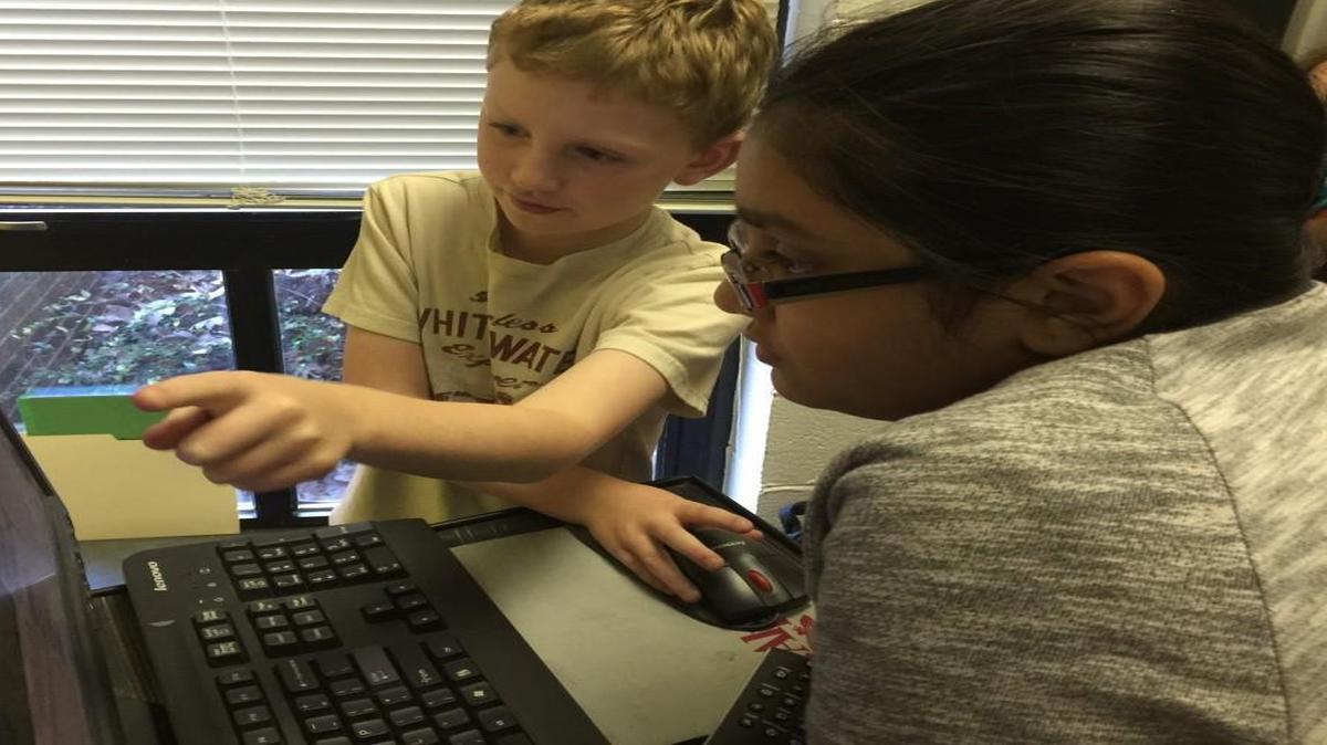 Malachy Fernandez, a fourth-grader at Powell Elementary School in Raleigh, shows a classmate how to use a computer program he created to round numbers to the nearest ten, hundred or thousand.