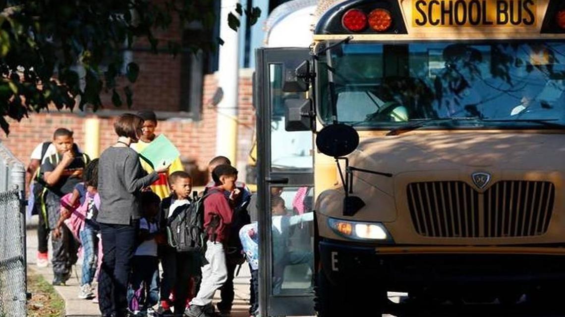 A Hunter Elementary School staffer sees her student charges safely to their school bus at Friday afternoon, October 30, 2015 at the end of the school day in east downtown Raleigh. Buses seemed to be running normally at Hunter Elementary on East Davie Street, but Friday the Wake County school system warned parents to expect delays of up to two hours getting students home from school because of mass bus driver absences Friday.