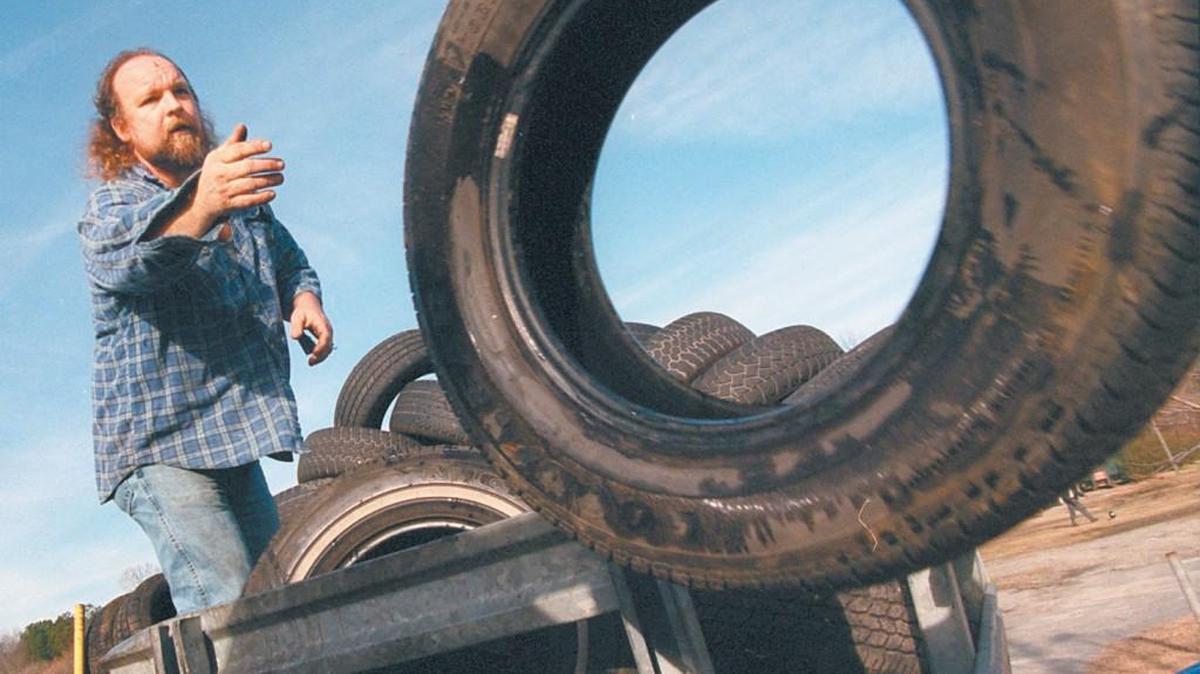 Kenneth Earp tosses used tires down to his son Duran to stack for sale at Watson's Flea Market off Rock Quarry Road in Southeast Raleigh in 2000. The YMCA of the Triangle now owns the site and wants to partner with the Wake County school system to build a joint Y/elementary school facility there.