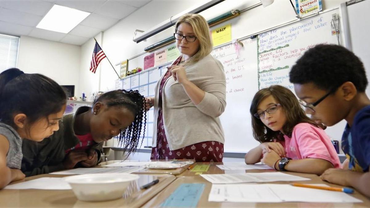 River Bend Elementary 5th graders, from left, Daniella Dorta, Parisia Morris, Greta Simon and Bishop Hooker read over a social studies exercise with teacher Savannah Meeks in class Thursday, September 15, 2016. River Bend has been a year round school since its beginning but now Wake County School administration is recommending that the school go to a traditional school year calendar.