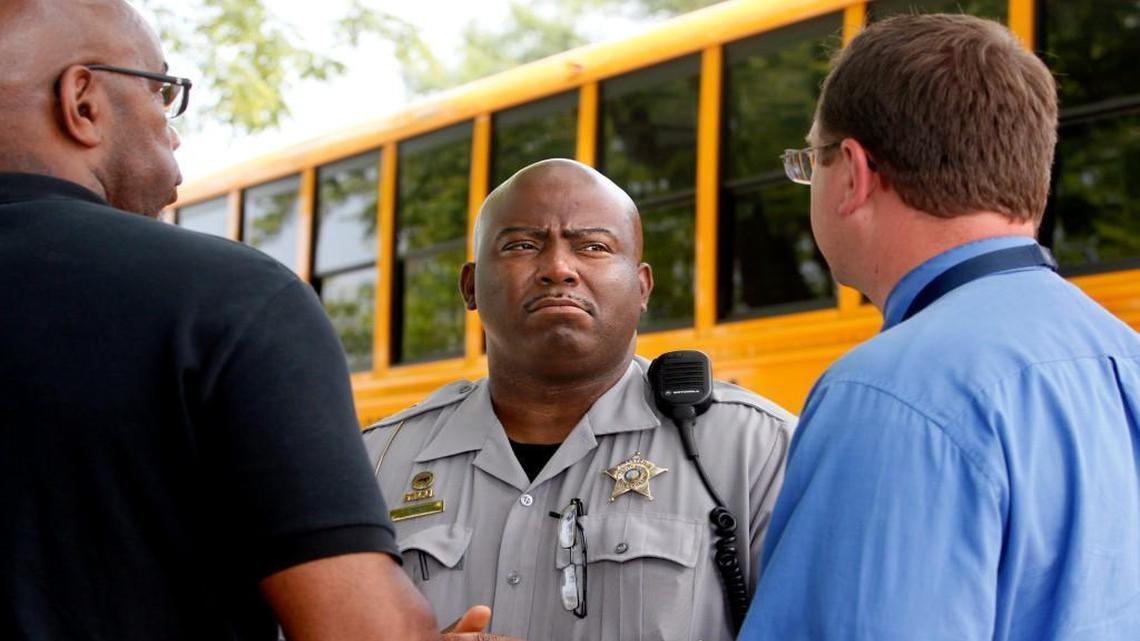 Wake County Sheriff's Deputy Sharron Bass, center, talks with Ronnie Sharpe, 8th grade assistant principal, left, and Curtis Brower, 7th grade assistant principal, right, while helping to oversee dismissal outside of Ligon Middle School in Raleigh on Tuesday, June 3, 2014. Wake County Sheriff Donnie Harrison is threatening to remove his deputies unless the school system develops a uniform policy on access to locker rooms and restrooms by transgender students.
