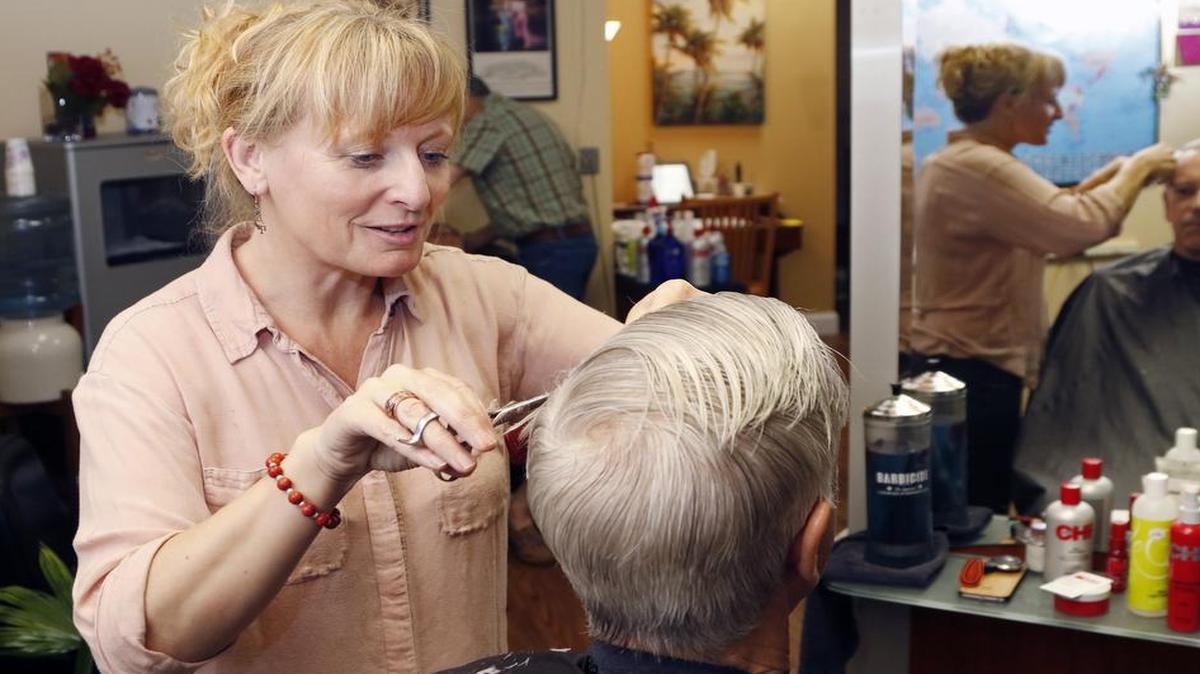 
Chapel Hill hairdresser Gail Markland, 50, finishes her trim and style on regular customer Jim Thomas of Carrboro at Fringe Salon. The native Briton, who emigrated to the U.S. in 1993, will graduate with a major in Spanish at UNC Chapel Hill’s commencement  thanks to the help of her regular customer – the late Bill Friday, who took an interest in Markland’s Durham Tech studies and helped her get in to UNC-Chapel Hill on a scholarship.
