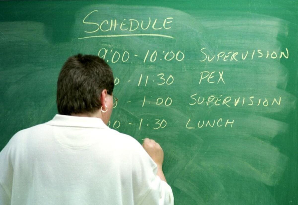 A teacher writes the schedule for the day on a blackboard.
