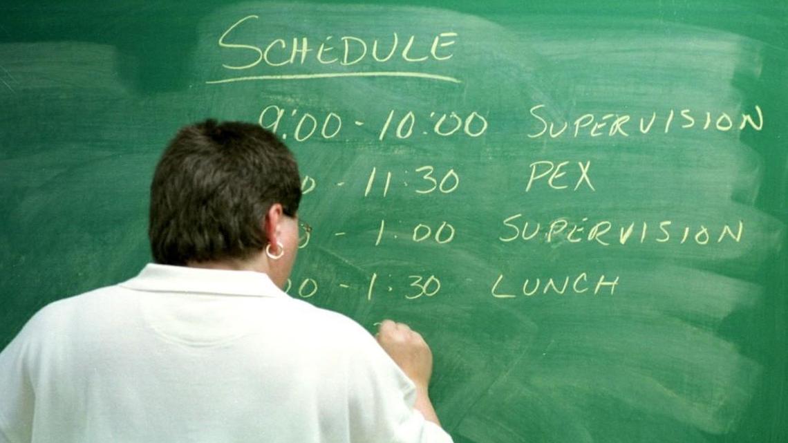 A teacher writes the schedule for the day on a blackboard.