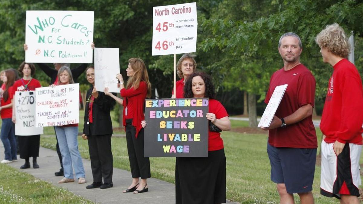Teachers, including Kristin VanBuskirk, center, a math teacher at Apex High School, rally against high turnover and low pay on the sidewalk in front of Apex High School on May 21, 2014.