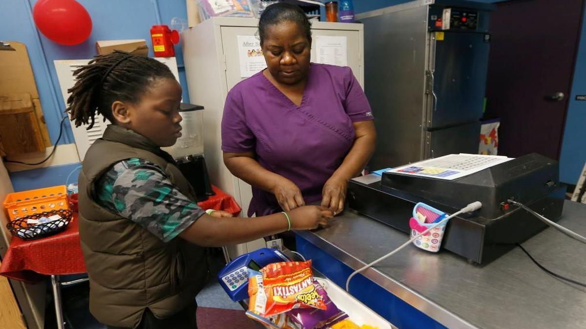 Fourth grader Nasir Stewart pays Tina Smith, lead manager with child nutrition for Wake County Public Schools, for lunch at Partnership Elementary School in Raleigh, N.C., on April 21, 2016.