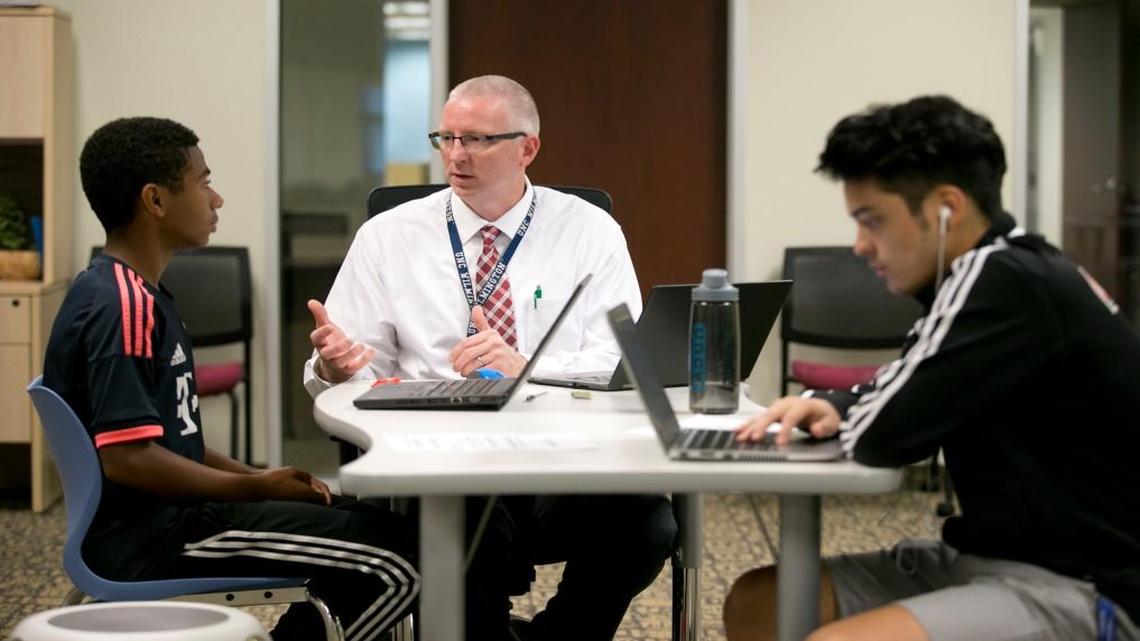 Crossroads Flex High School teacher Keith Lindsay works with students Kevan Kahoussi, left and Josue Deleon on Sept. 21, 2016 in Cary, N.C.  A new policy being considered by the Wake County school board would set rules on how employees communicate electronically with students.