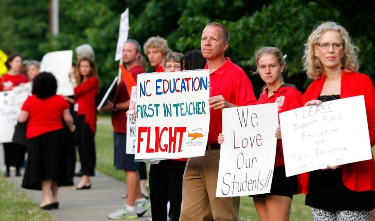 Scott Ferguson, center, an English teacher at Apex High School, rallies with fellow teachers and supporters against high turnover and low pay of teachers on the sidewalk in front of Apex High School on May 21, 2014.