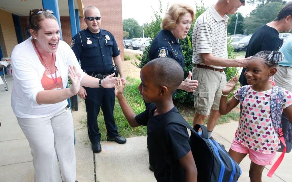 Cathie Linkous, a kindergarten teacher, left, and Fuquay-Varina police chief Laura Fahnestock, right, are two of the number of members of the community and teachers who greeted students during the first day of school at Lincoln Heights Elementary School in Fuquay-Varina, N.C., on Aug. 29, 2016. Lincoln Heights may receive a magnet program to try to fill and diversify the school.