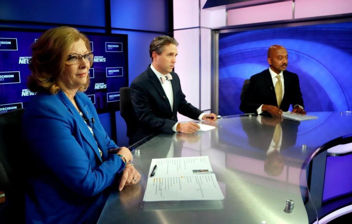 Candidates for Raleigh Mayor Nancy McFarlane, left, and Charles Francis, right, and moderator Tim Boyum, center, get ready before a debate at Spectrum News studios in Raleigh on Oct. 20.