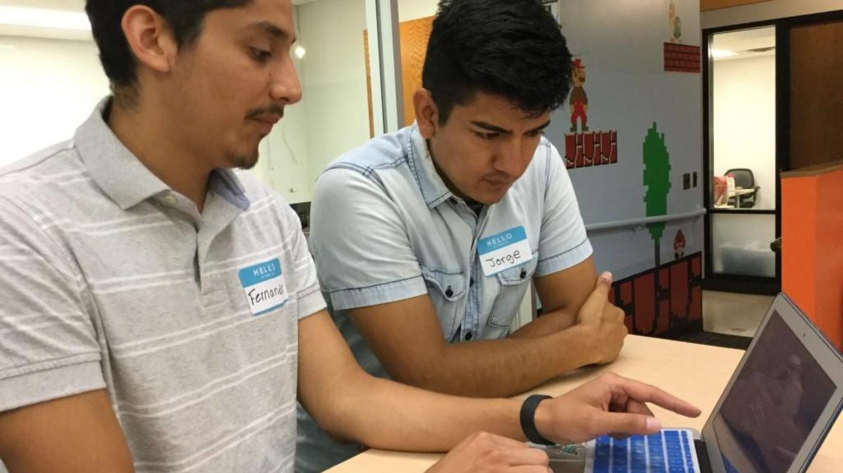 Fernando Osorto, left, and Jorge Rodriguez discuss an app they developed for Student Action with Farmworkers through the Code the Dream project sponsored by Uniting NC. Osorto and Rodriguez spoke at Code the Dream classes on July 29, 2017, at the American Underground in Durham, NC.