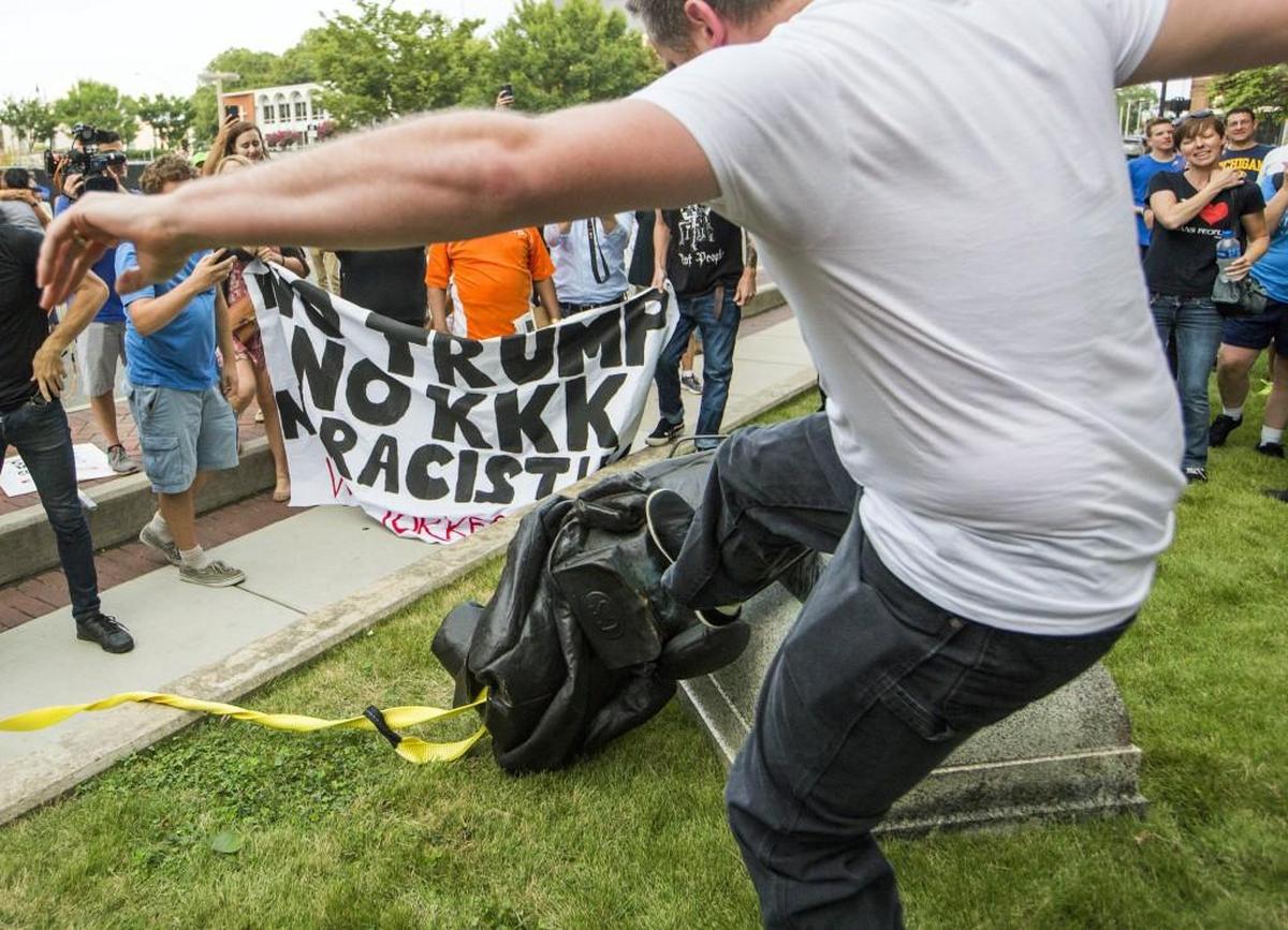 A group of protesters cheer and take turns kicking a toppled Confederate soldier statue at the old Durham County Courthouse on Monday, Aug. 14, 2017, in Durham, North Carolina.