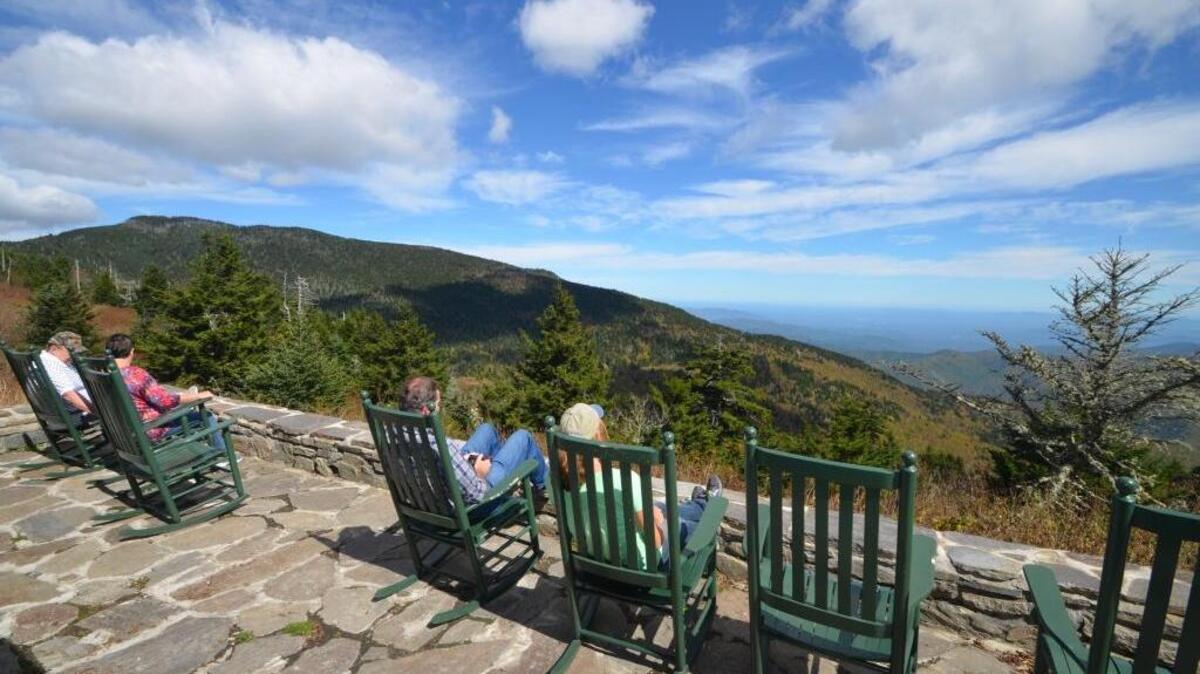 Relaxing beneath the crown of Mount Mitchell, visitors gaze across Mount Mitchell State Park lands from the porch of the park restaurant in October. The park celebrates its 100th year in 2016.
