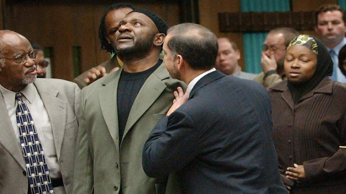 Darryl Hunt, second from left, standing between attorneys James Ferguson, left, and Mark Rabil, third from left, reacts after being cleared of a murder charge during a court hearing in Winston-Salem, Feb. 6, 2004. At right is Hunt's wife April. Hunt was found dead in a truck near Wake Forest University on Sunday.